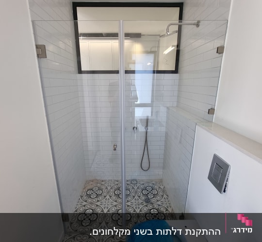 מקלחת עם דלת זכוכית, ראש מקלחת וקירות אריחים לבנים